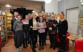 Grupa osób uczestniczących w spotkaniu. Po bokach stoją czerwone fotele.