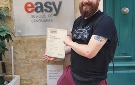 Młody mężczyzna pozuje do zdjęcia przed easy school of languages.