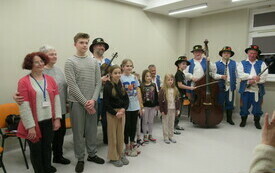 Grupa osób: dzieci, zespół muzyczny w strojach ludowych pozuje do wspólnego zdjęcia