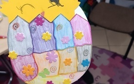 Pisanka z papieru, wyklejona kwiatuszkami, w środku kurczak. 