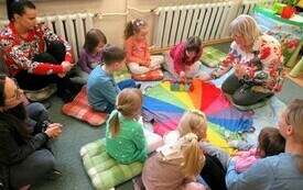 Na dywanie grupa dzieci wraz z opiekunami. 