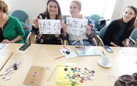 Dwie kobiety prezentują wykonane rysunki z chińskimi znakami. 