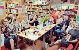 Grupa czytelnik&oacute;w pozuje do zdjecia w bibliotece trzymając w rękach książki
