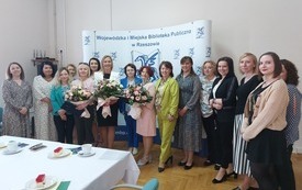 Grupa szesnastu kobiet pozuje na stojąco do wspólnego zdjęcia