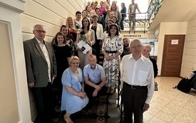 Grupa osób pozuje do wspólnego zdjęcia na zabytkowej klatce schodowej w bibliotece