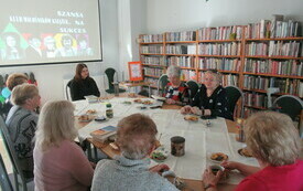 Sala biblioteczna, przy stoliku seniorki z bibliotekarką.