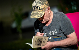 Mężczyzna w czapce z daszkiem czyta "Wiersze dla ludu polskiego"