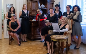 Grupa kobiet stoi obok siebie, częśc siedzi na fotelu.