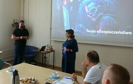 Kobieta z teczką oraz mężczyzna na środku sali.