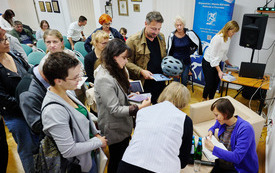 Kobieta chabrowym sweterku wpisuje dedykację do książek.