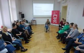 Grupa bibliotekarz z województwa podkarpackiego siedzi w kręgu, w tle baner z DKK.