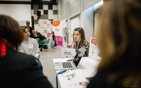 kobieta z tabliczką w ręce opowiada pozostałym.