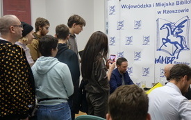 Łona podpisuje płyty, grupa ludzi stoi w kolejce.