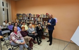Męzczyzna w marynarce wraz z grupą kobiet pozuje do wsp&oacute;lnego zdjęcia.