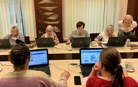 Słuchające kobiety pracują przy komputerach.