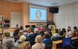 Widownia na krzesłach uczestnicząca w spotkaniu. 