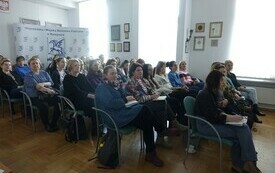 Widok na widownię siedzącą na krzesłach.