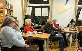 Uczestnicy spotkania siedzący przy stolikach.