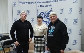 Bibliotekarka i dw&oacute;ch mężczyzn w charakterystycznych czapkach. 