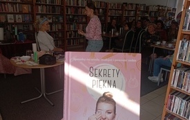 Książka o tematyce urodowej, a w tle pokaz makijażu.