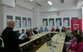 Prowadzący stoi przez salą wypełnioną uczestnikami szkolenia