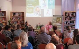 Sala biblioteczna wypełniona uczestnikami spotkania.