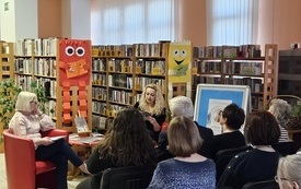 Grupa ludzi zebranych na spotkaniu w bibliotece.