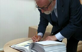 Mężczyzna wpisujący się do kroniki biblioteki. 