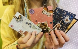 Dziewczynka trzymająca w ręku kartki wykonane metodą scrapbookingową