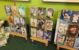 Trzy sztalugi na kt&oacute;rych wyeksponowano kartki wykonane metodą scrapbookingową