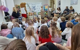 Dzieci, mamy oraz bibliotekarki zgromadzone w sali.