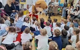 Miś Uszatek przybija piątkę z dziećmi.