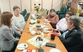 Kilka osób dyskutuje przy stole.