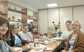 Kilkao kobiet siedzi przy stole i patrzy w stronę fotografa.