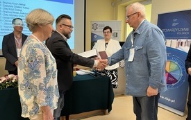 Starszy mężczyzna odbiera odznaczenie.